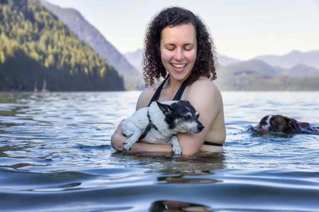 Woman swimming in a lake with dog